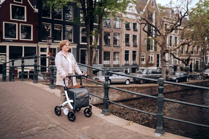 a woman pushing a stroller down a street next to a river